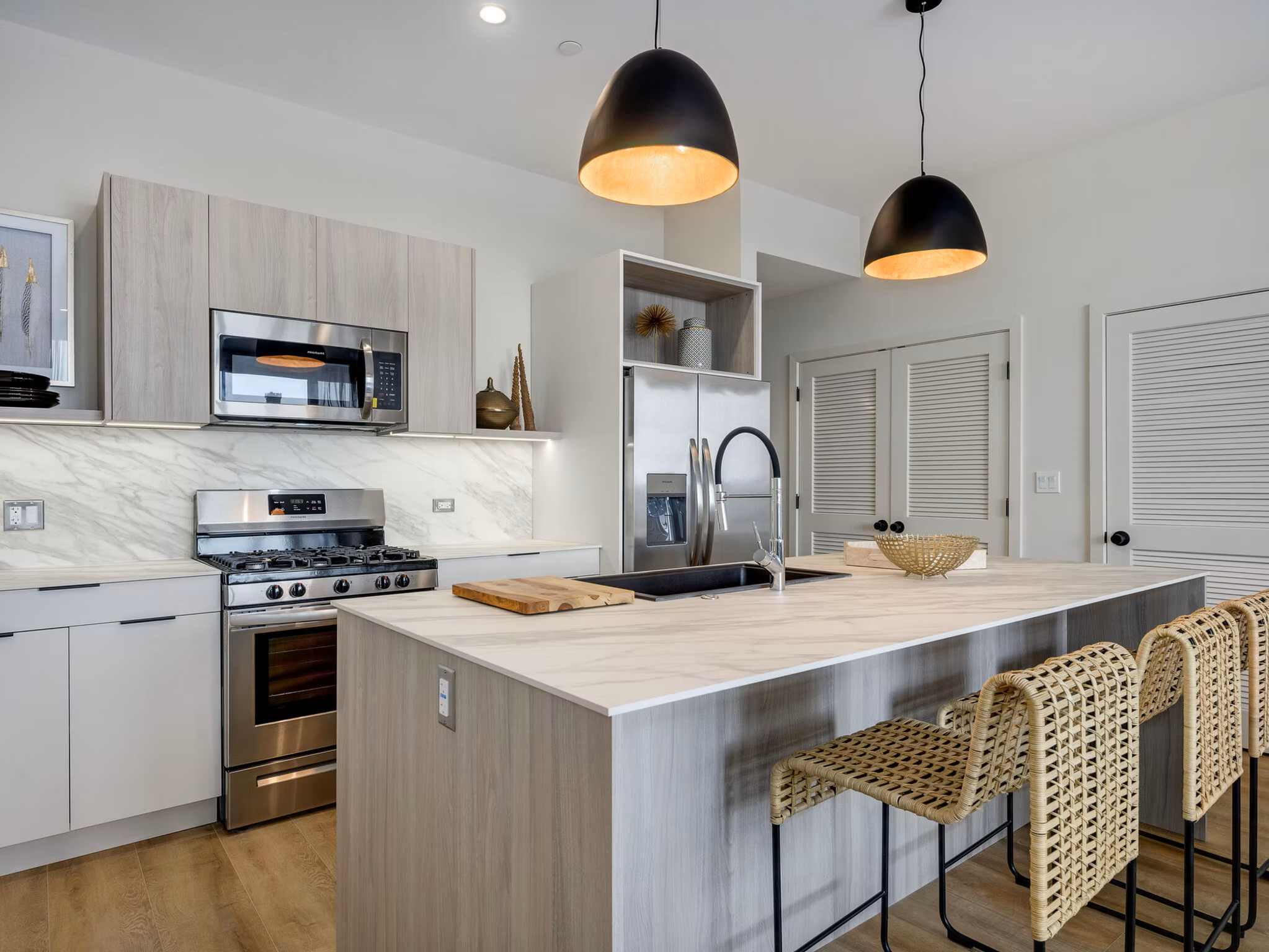 Modern kitchen with island, barstools, pendant lights.