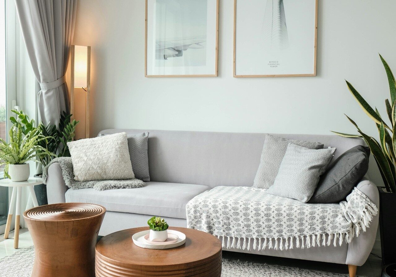 Modern living room with gray sofa and wooden tables.
