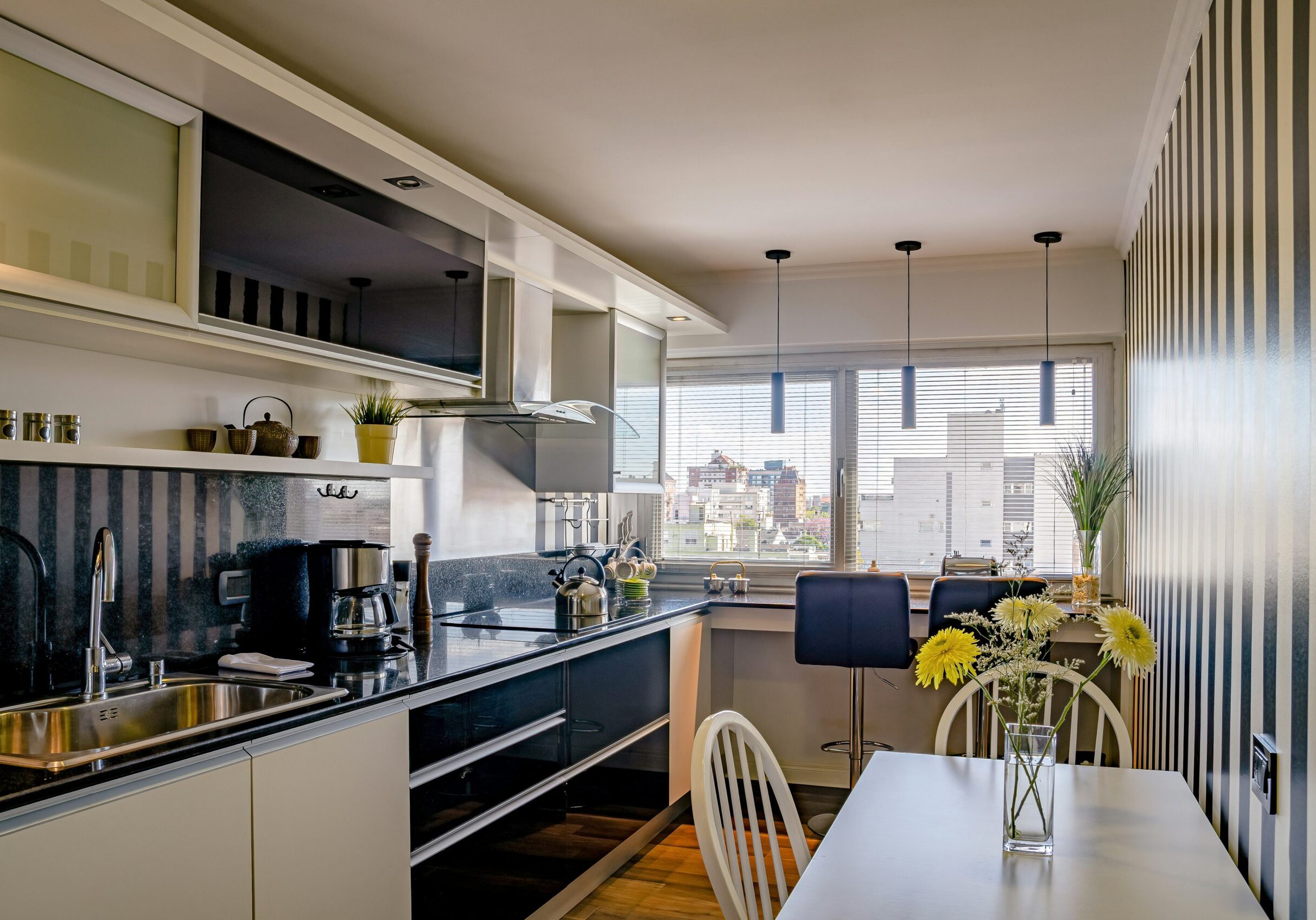 Modern kitchen with city view and flowers.