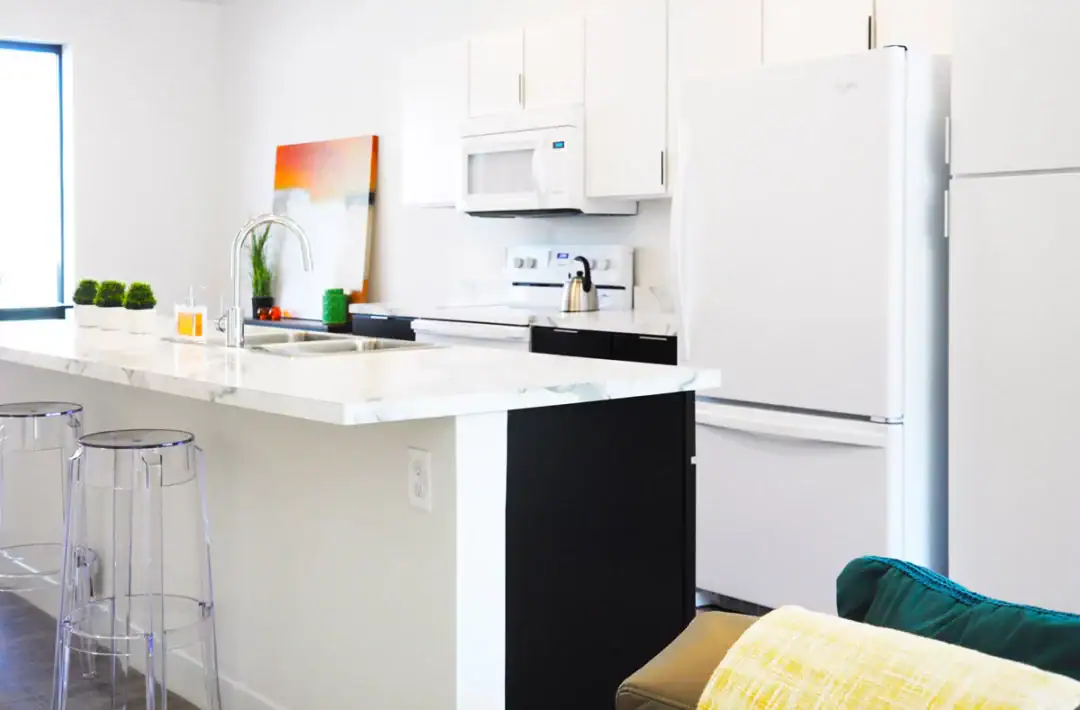 Modern kitchen with white cabinets and marble countertop.