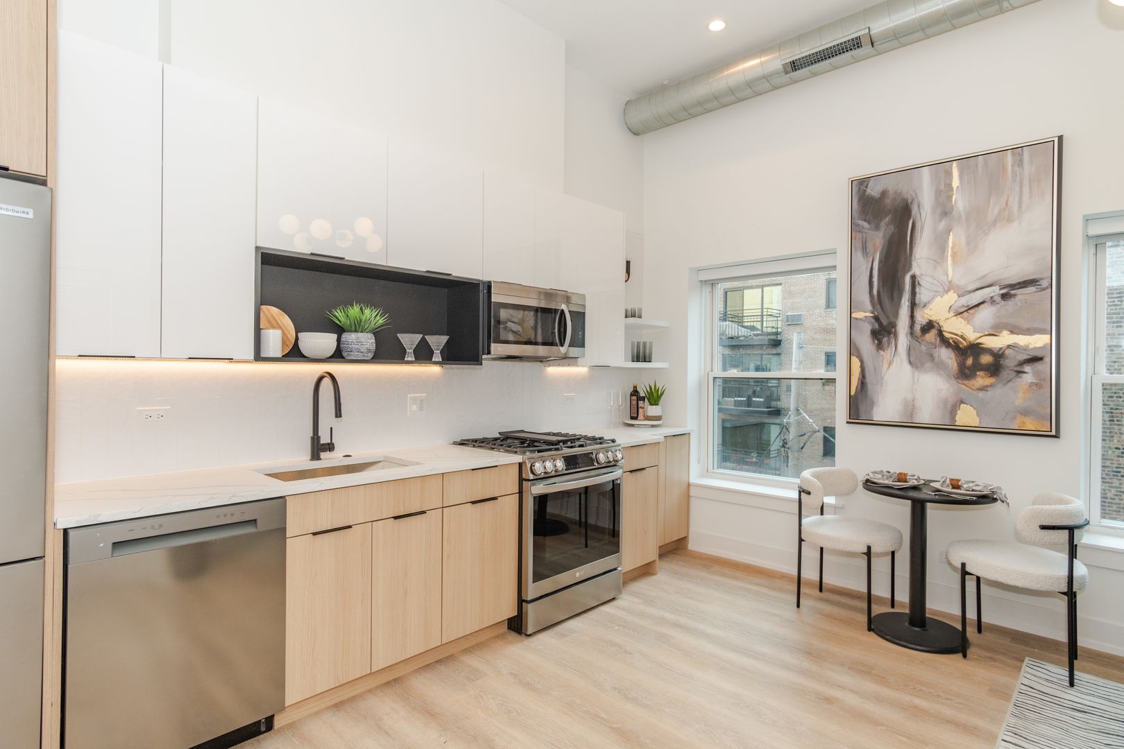 Modern kitchen with stainless steel appliances and artwork.